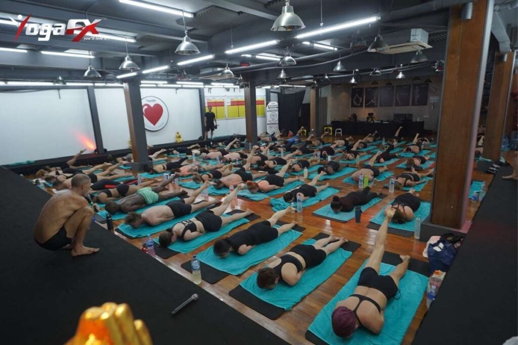 An instructor offering posture modifications to support a first-time hot yoga student