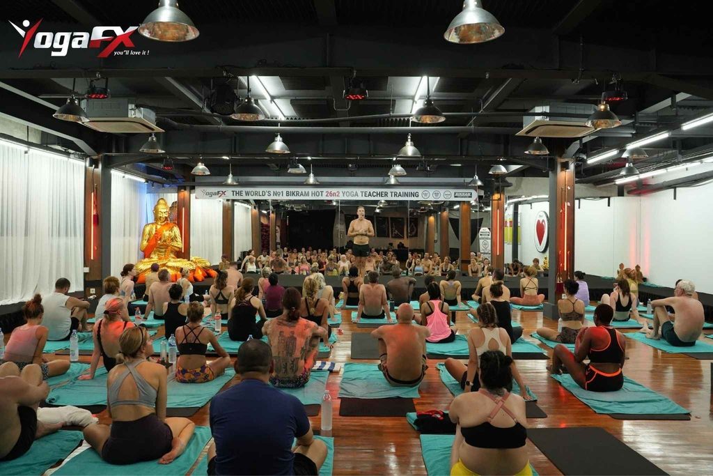 Mr. Ian Terry giving direct posture correction to a Bikram yoga teacher training candidate in natural tropical heat at YogaFX Seminyak, Bali