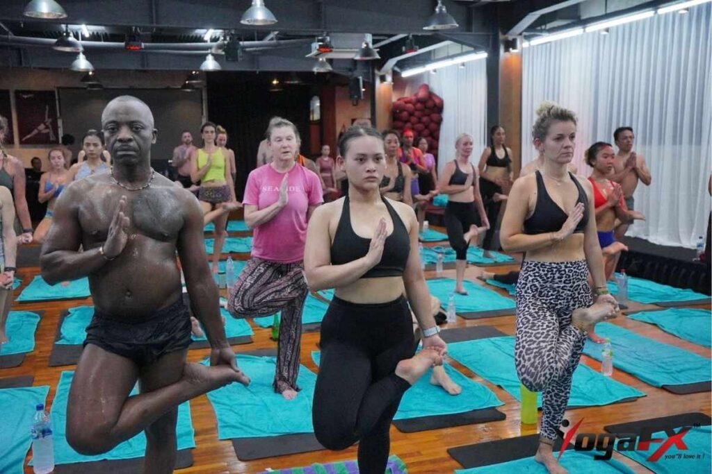 Split comparison of online video study versus a heated in person classroom, illustrating what online hot yoga teacher training can and cannot replace.