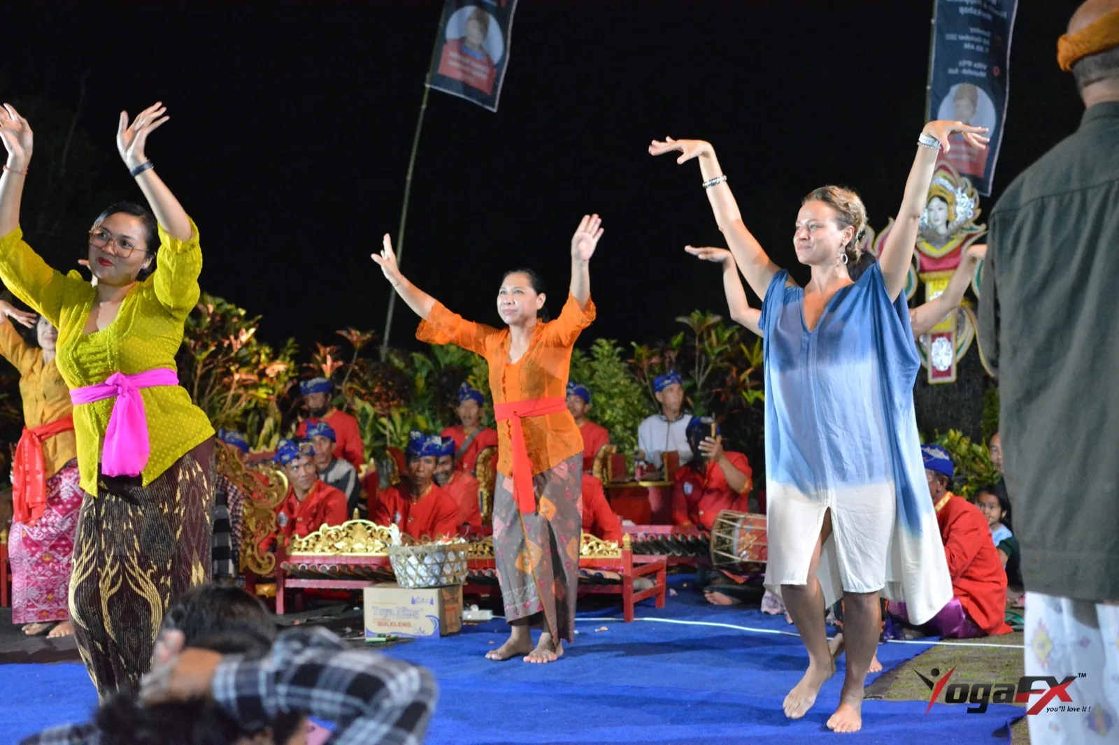 Balinese dancers and a YogaFX student at an evening cultural event, part of a slower Bali wellness day after hot yoga and sauna